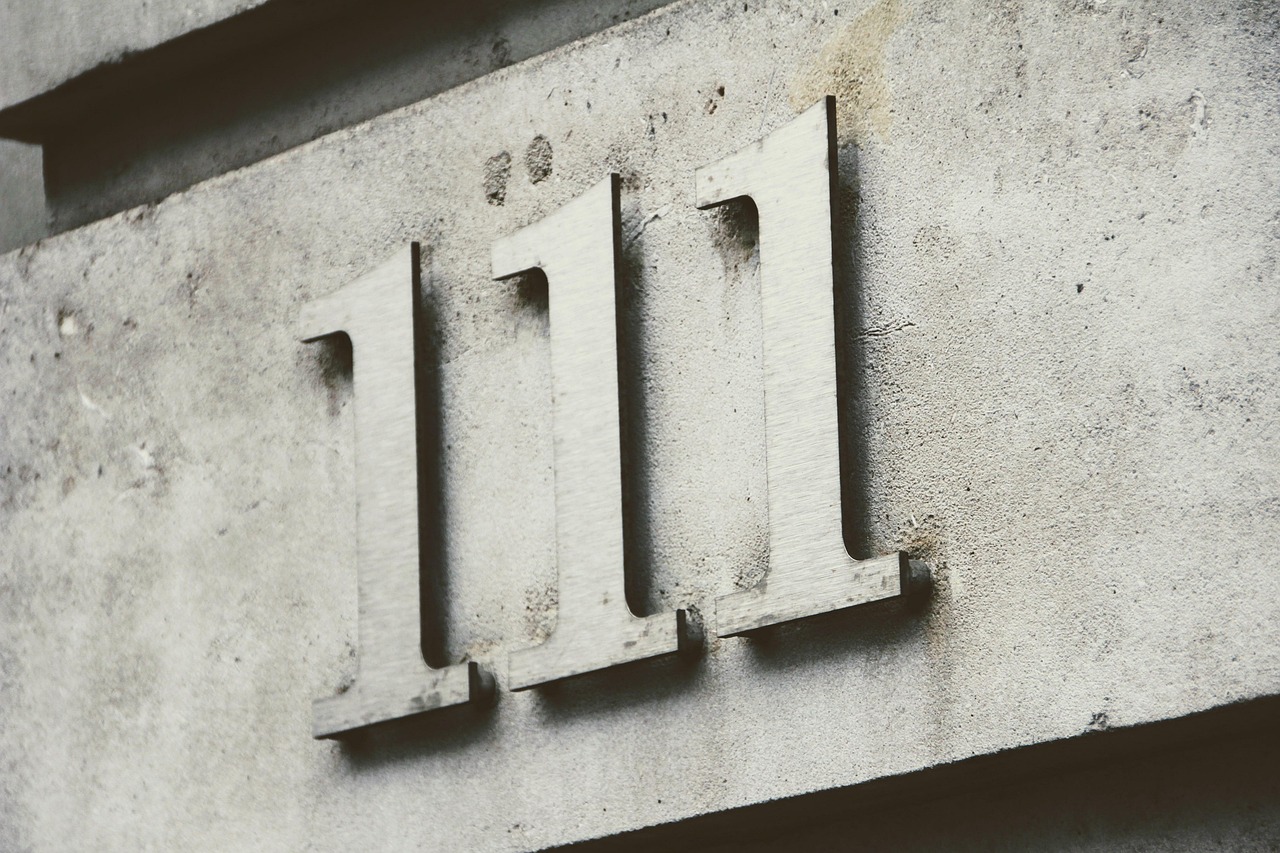 Metallic numbers &lsquo;111&rsquo; on a textured concrete wall.