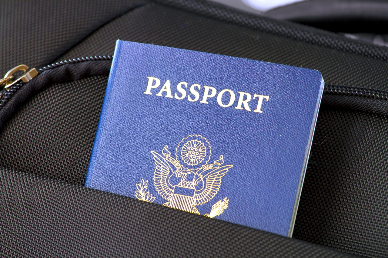 A blue US passport partially visible in a black luggage pocket.