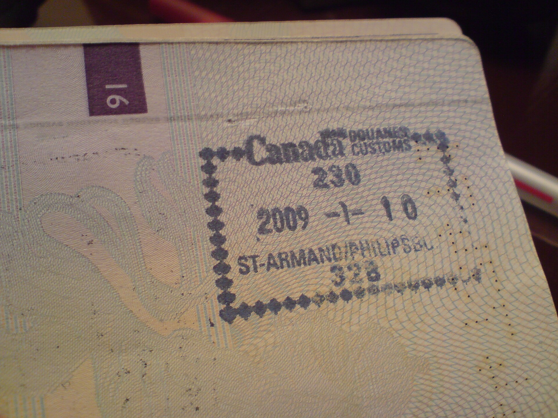 Close-up of a passport page with a blue Canadian customs entry stamp dated 2009.