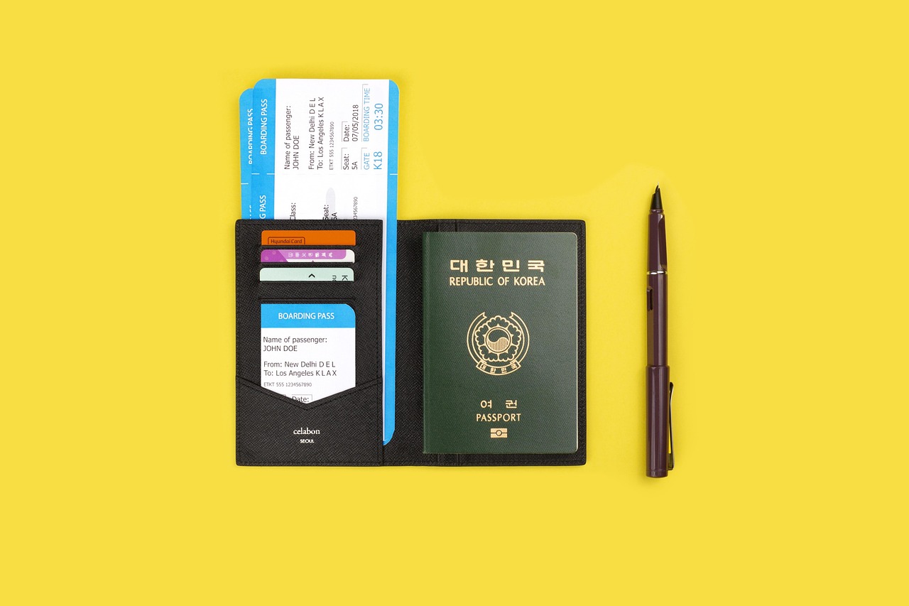 A green Republic of Korea passport, boarding passes, and cards in a black passport holder on a yellow background with a pen.