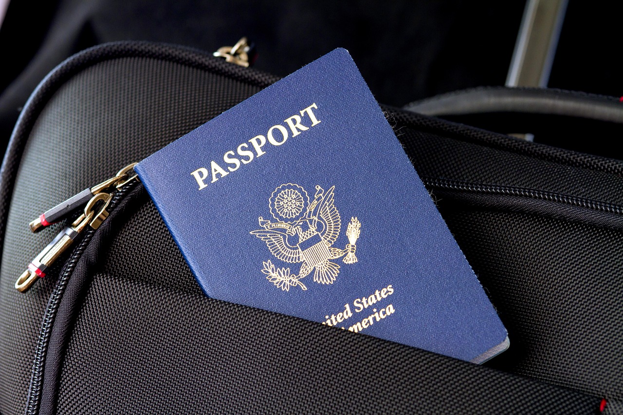 Blue United States passport partially tucked into a black travel bag pocket.