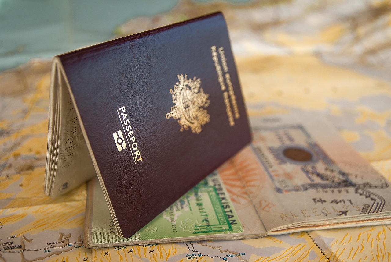 A dark red French passport, partially open, rests on an open map showing travel stamps.