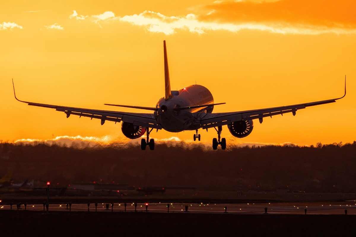 Air Canada ID rules for visitors: an airliner landing against an orange sunset sky