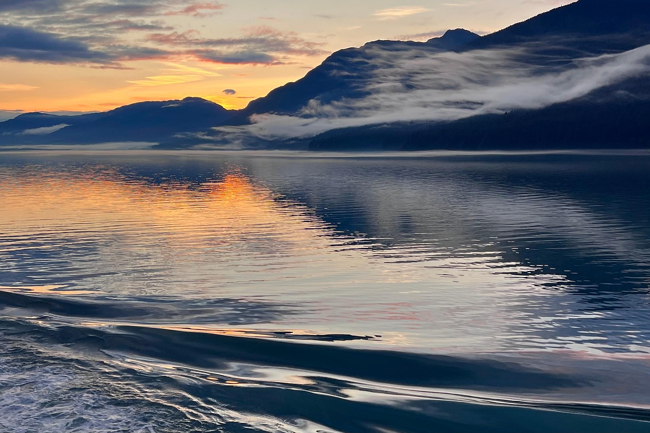 Alaska cruise, Canada visa or eTA: sunset over the Inside Passage with mist on the mountains and a ship's wake in the foreground