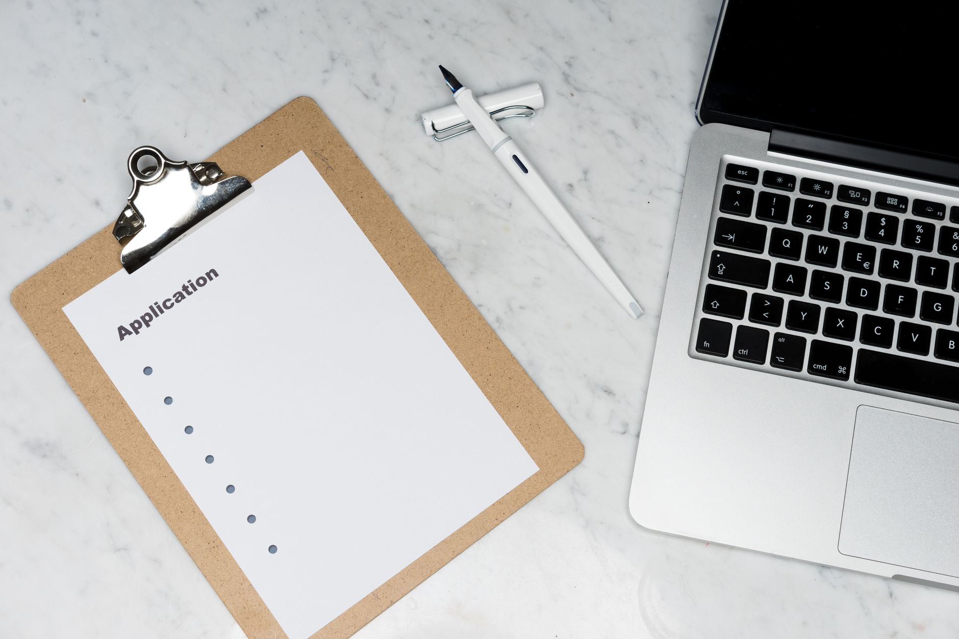 Application checklist on a clipboard beside a laptop