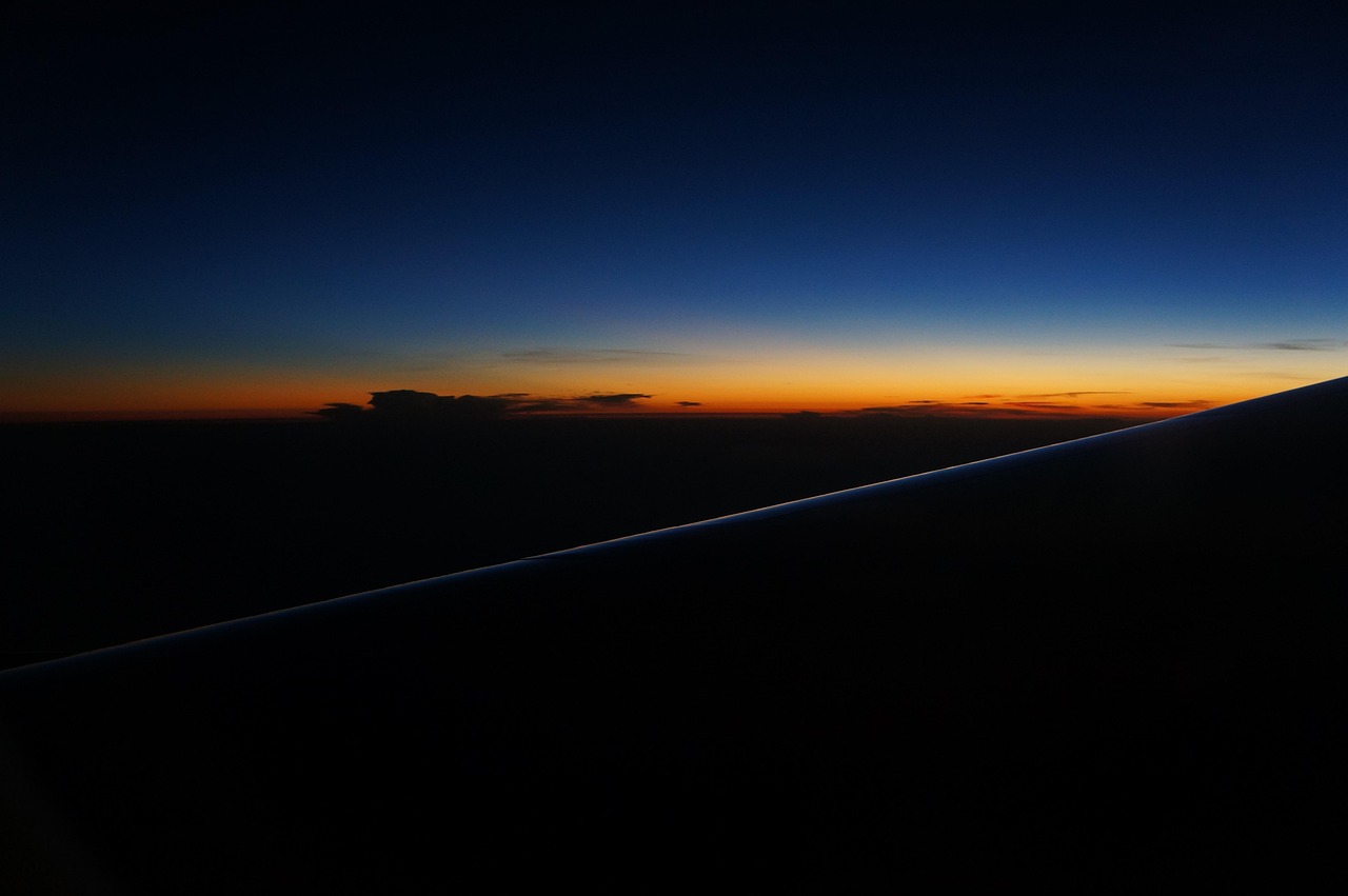 Canada eTA for New Zealanders: an aircraft wing against a deep blue and orange dusk sky on a long flight