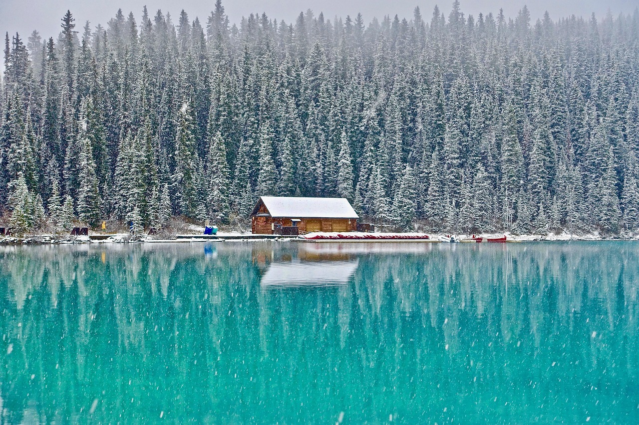 Canada eTA for Swedish Citizens: a snowy log boathouse and conifer forest on a turquoise lake