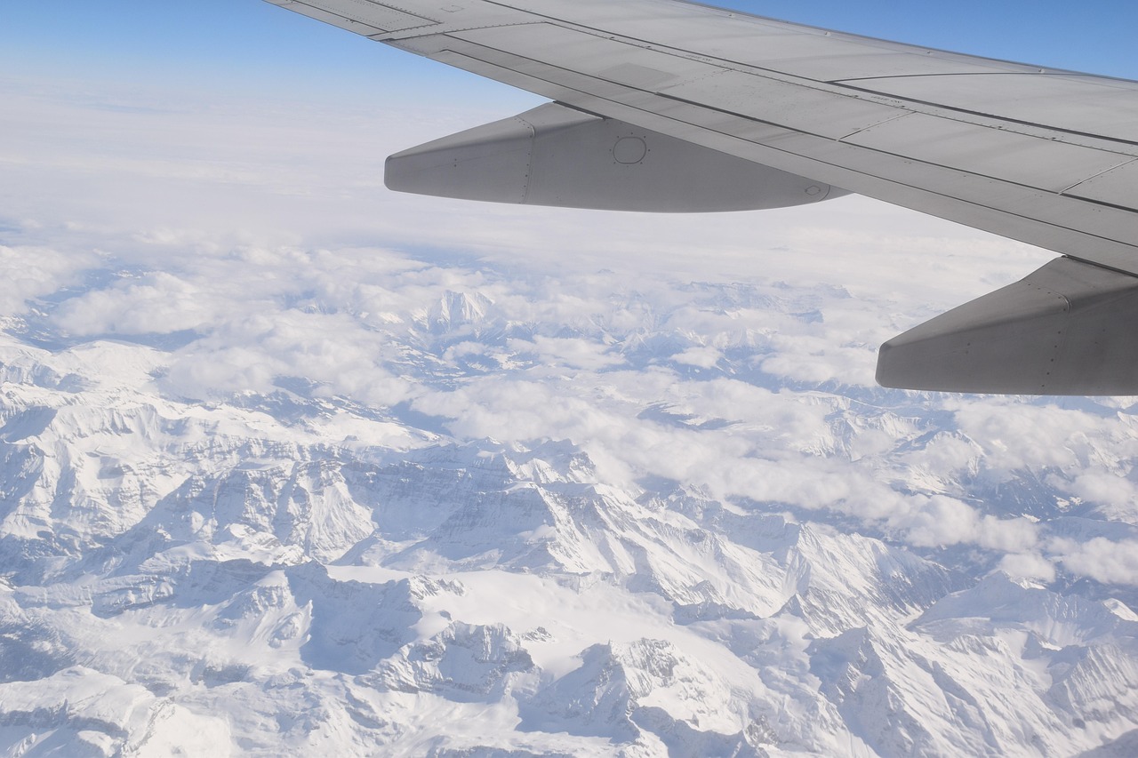 Canada eTA for Swiss Citizens: an aircraft wing above snow-covered Alpine peaks and clouds