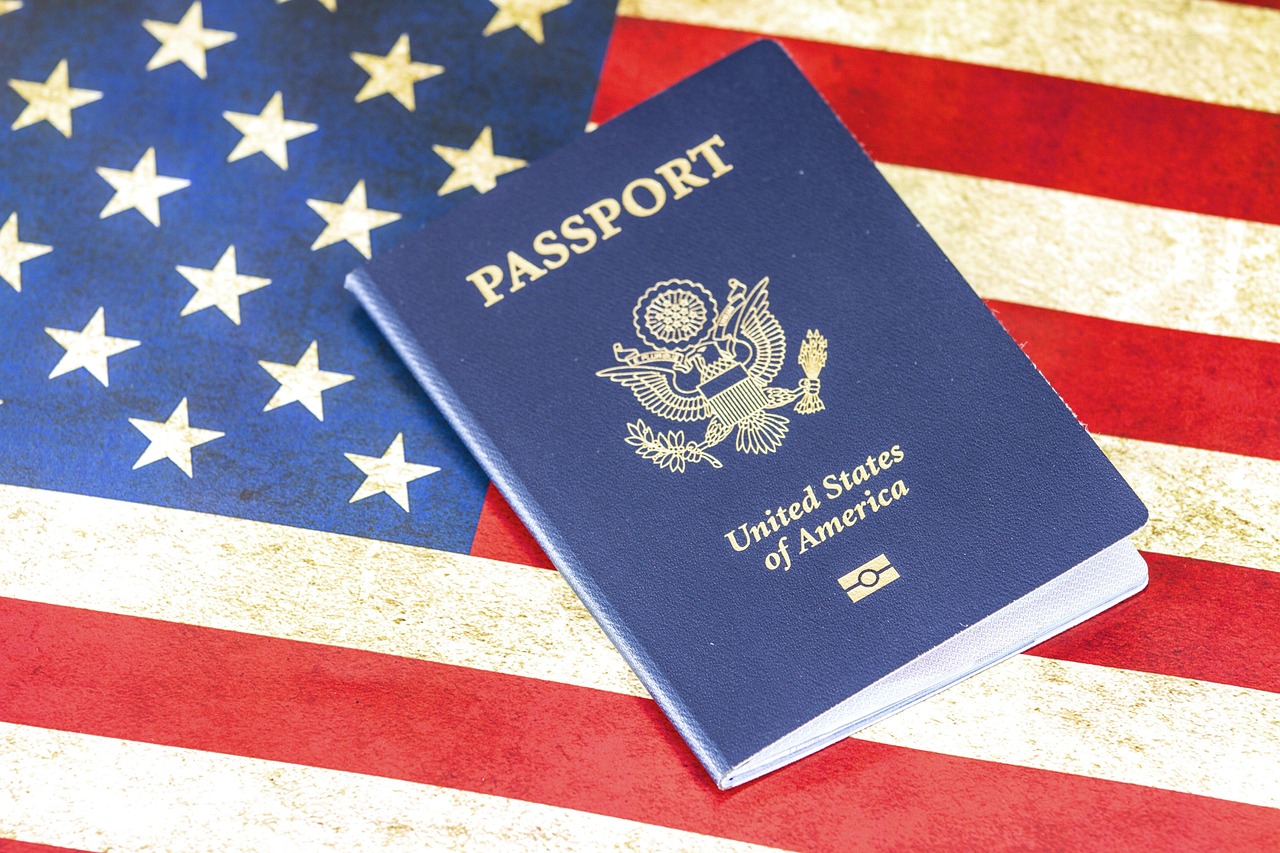 A blue United States passport rests on an American flag, showing the passport cover and flag details.