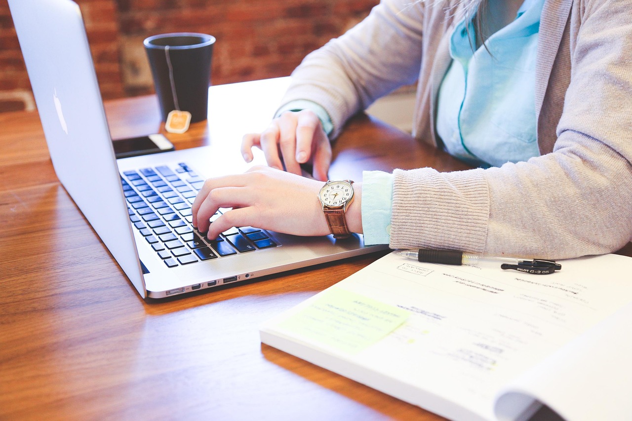 Do Students With a U.S. Visa Need a Canadian eTA: person typing on a laptop next to a notebook and a cup of tea
