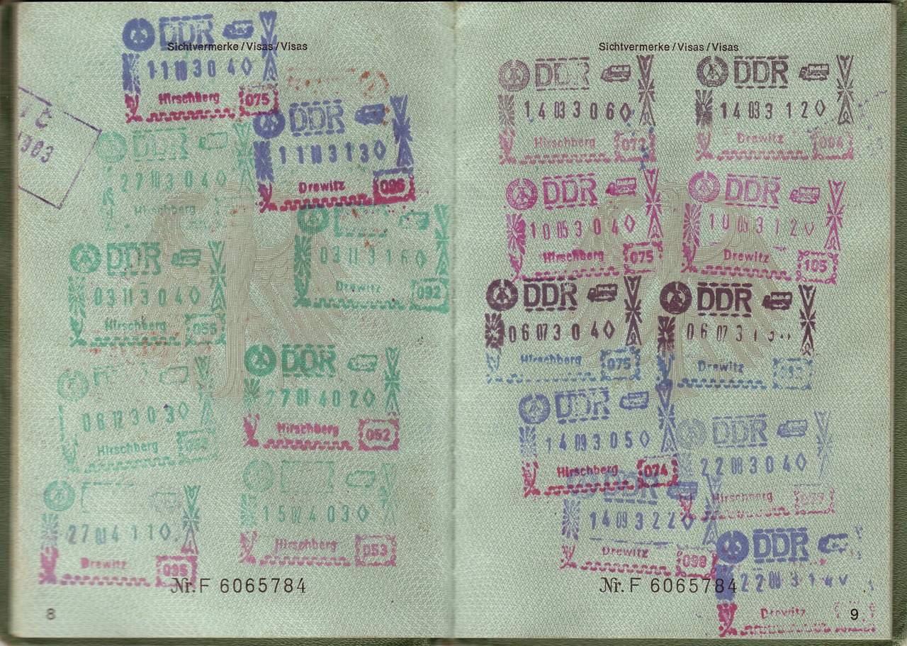 Passport pages filled with numerous colorful visa and transit stamps from the former German Democratic Republic (DDR).