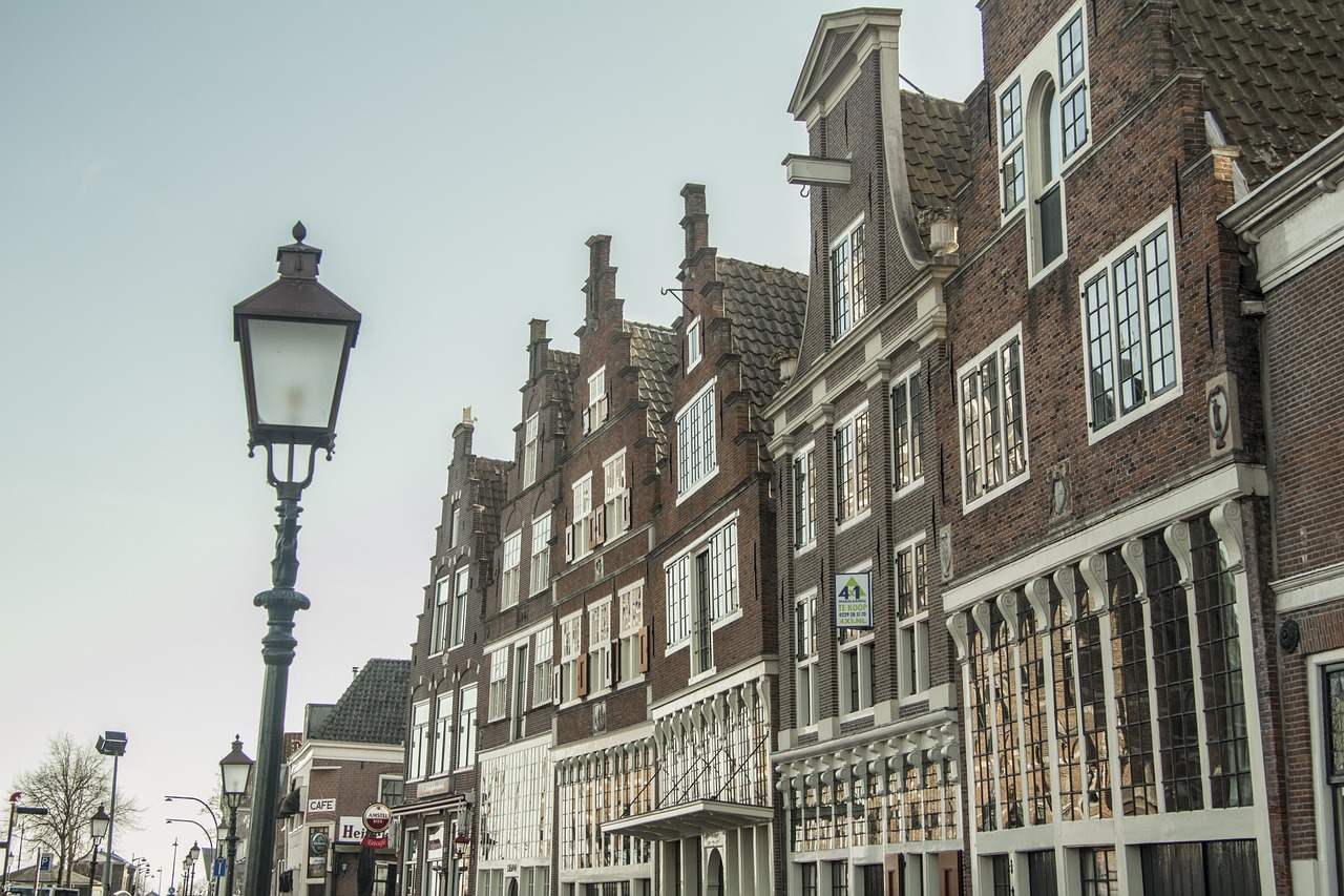 A row of traditional brick buildings with stepped gables and a tall black street lamp under a light sky.