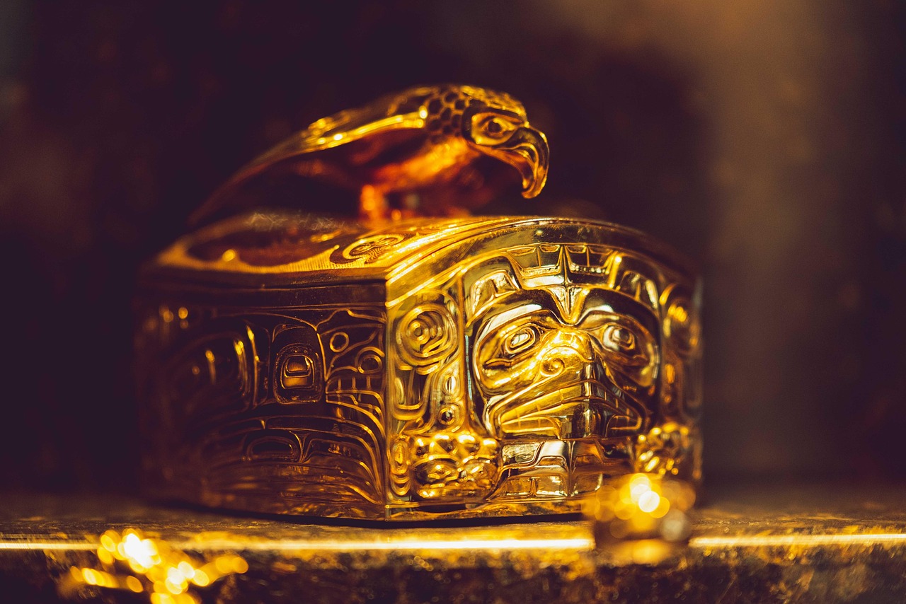 Golden ornate box with indigenous-style carvings and a bird figure on the lid.